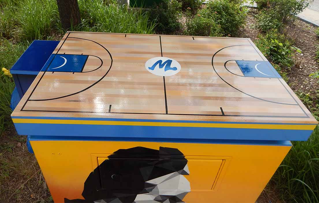 The top of the utility box mural features a baskeball court.