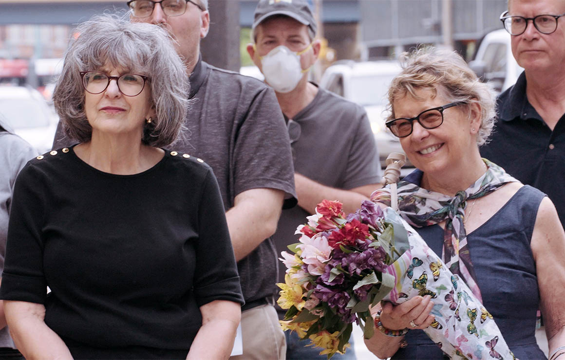 Rachel Forman, director of the Grand Avenue Club, stands with another woman holding flowers.